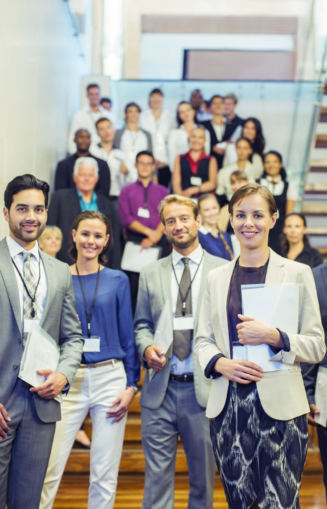 Portrait of men and women standing in lobby of conference center Gruppe von Menschen verschiedenen Alters mit zufriedenen Gesichtern.